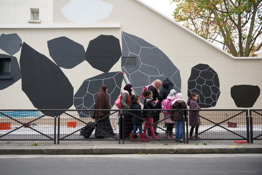 Schoolkids si radunano davanti a il murale sul lato della loro scuola