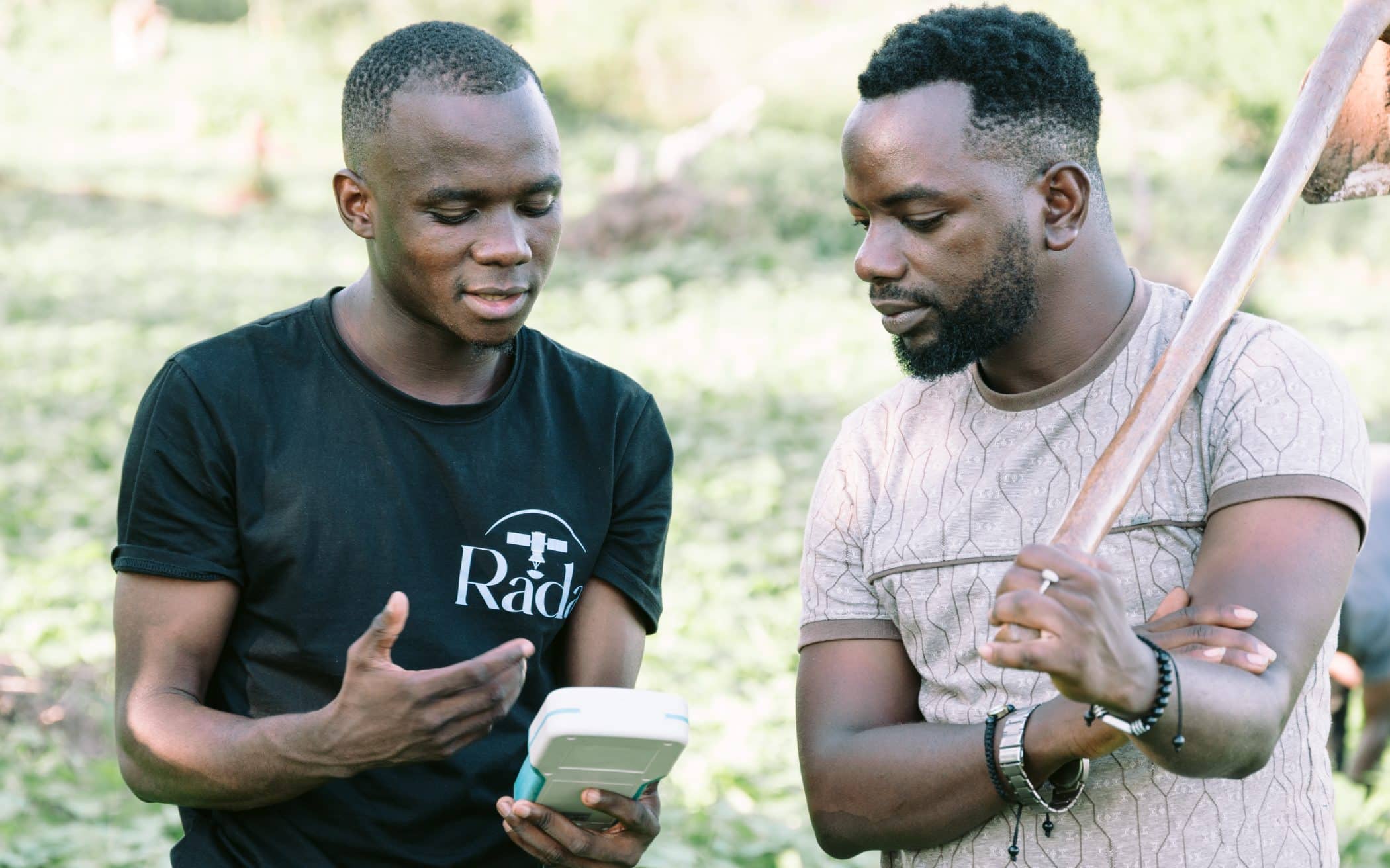 Two farmers discussing over device for AI-powered precision farming