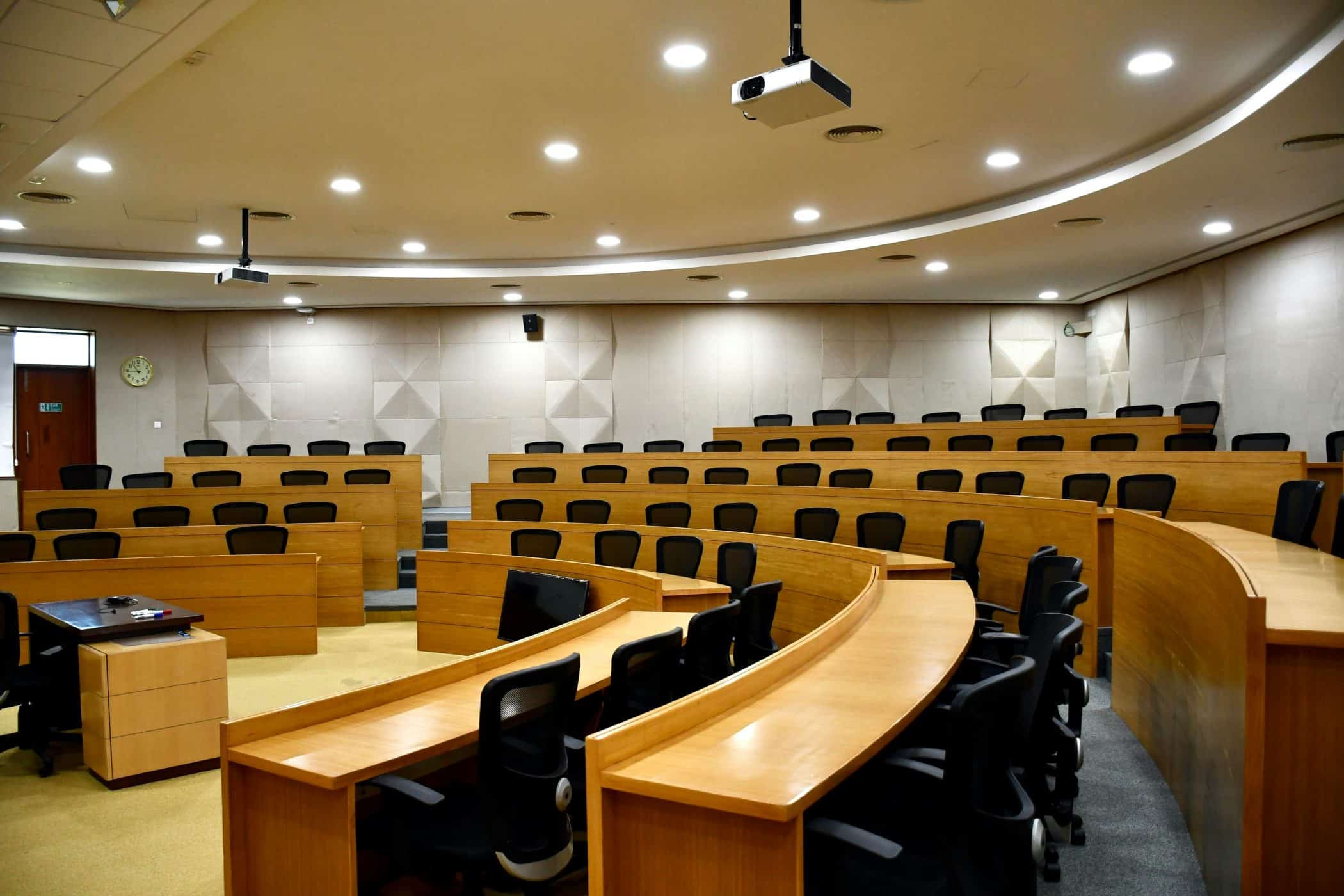 A conference room with wooden desks and empty seats